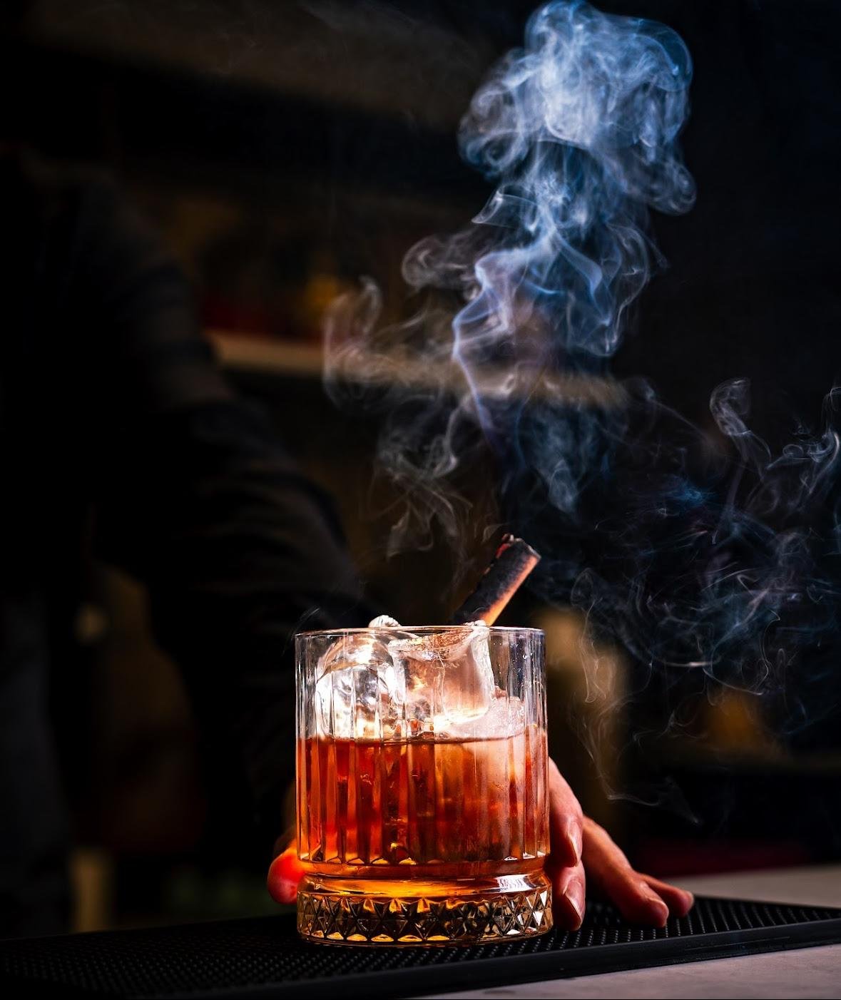 A cocktail with a smoking garnish at Saffron Table